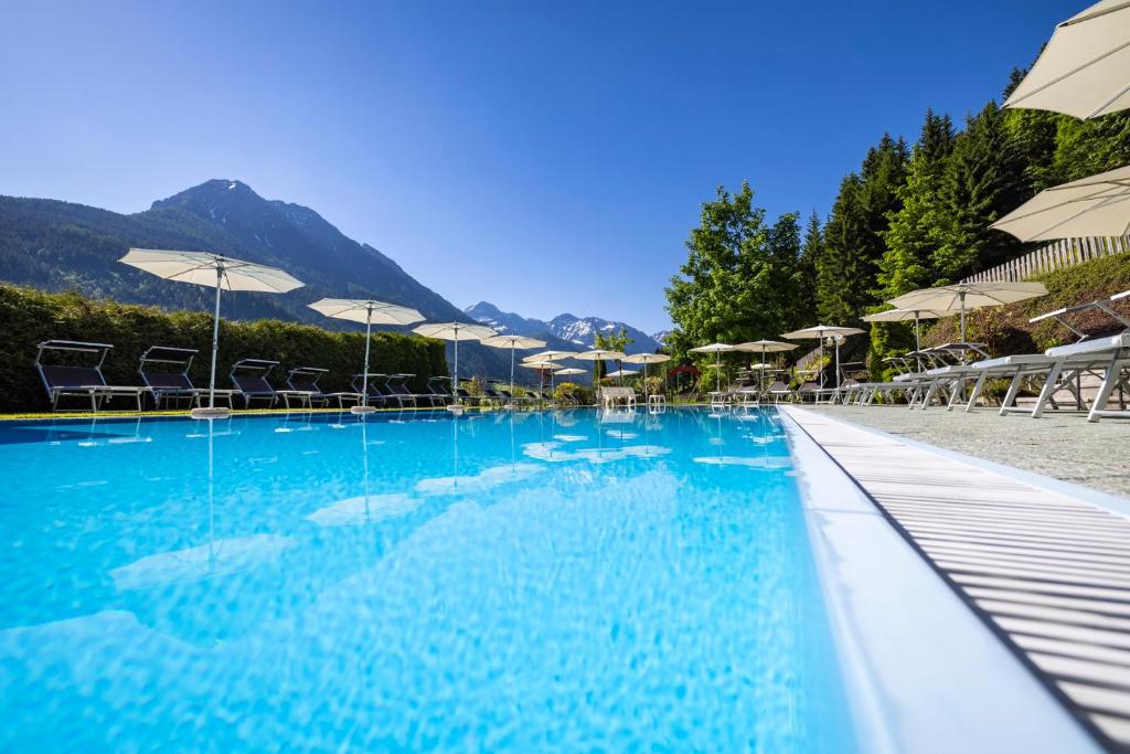 a swimming pool with chairs and umbrellas on a beach at Wellness-Aparthotel Montana in Kleinarl
