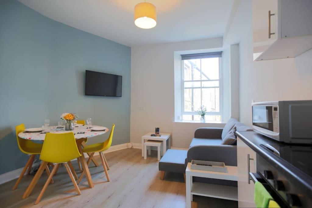 a living room with a couch and a table with yellow chairs at Cosy & Central Broughton 2BR Apt near City Centre in Edinburgh