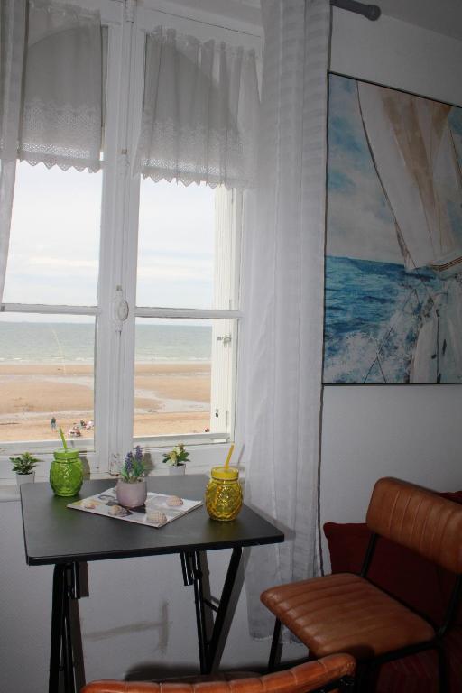 - une table en face d'une fenêtre avec vue sur la plage dans l'établissement Au Paradis de la Mer A 10m de la mer, à Villers-sur-Mer