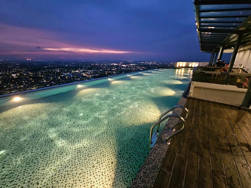 una piscina en la parte superior de un edificio con ciudad en Quartz Paragon Suites Melaka By GGM, en Melaka