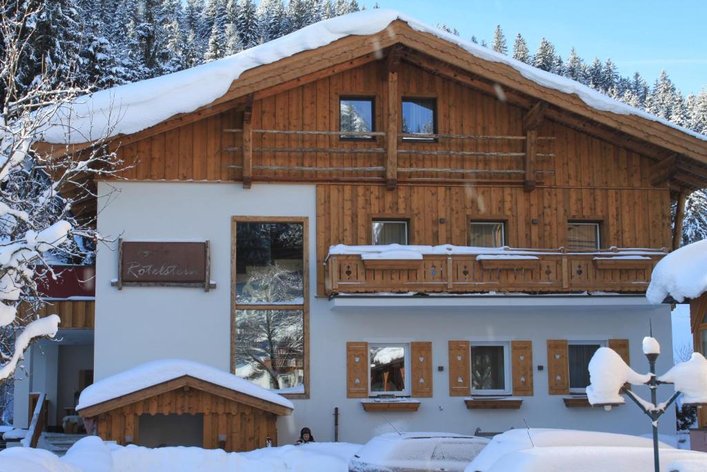 una casa de madera con nieve en el techo en Appartements Haus Rötelstein, en Filzmoos