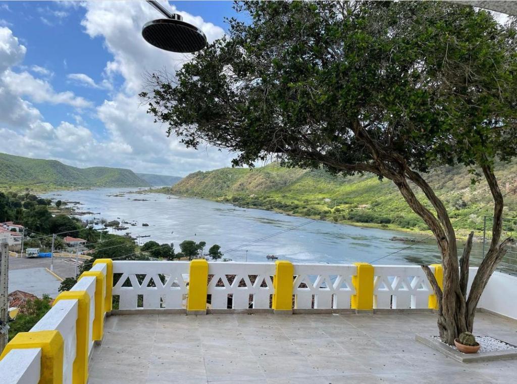 Blick auf einen Fluss mit einem gelben Zaun und einem Baum in der Unterkunft Casa Bela Vista in Piranhas