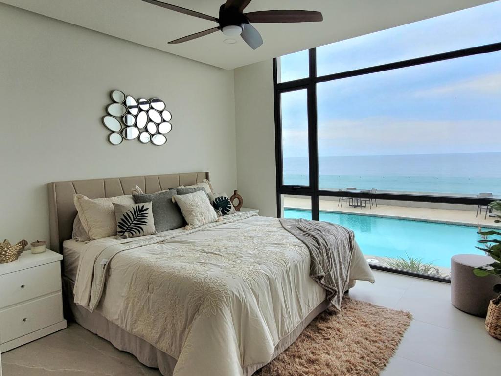 a bedroom with a large bed and a swimming pool at Seafront Luxury Condo in Rosarito with Pool & Jacuzzi in Rosarito