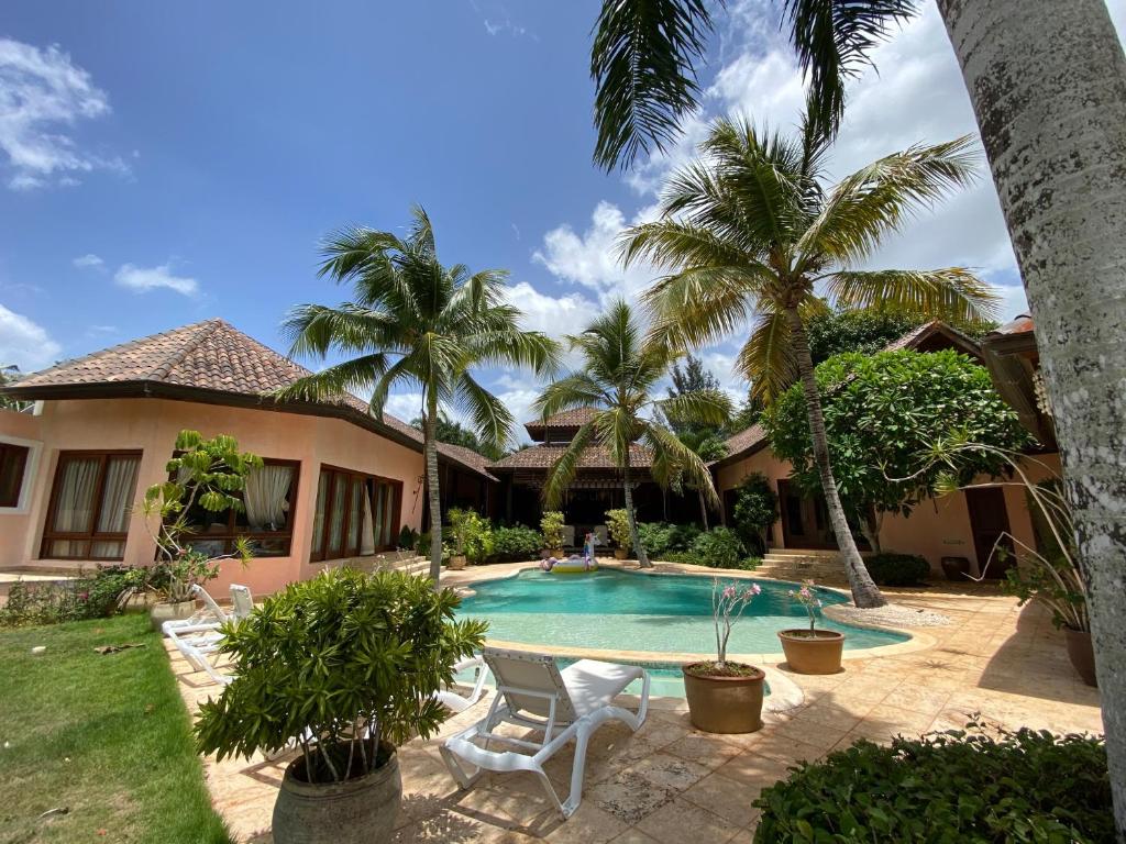 a house with a swimming pool and palm trees at 5-Bedroom Villa with Private Pool, Maid and Golf Course Views at Casa de Campo Resort in La Romana