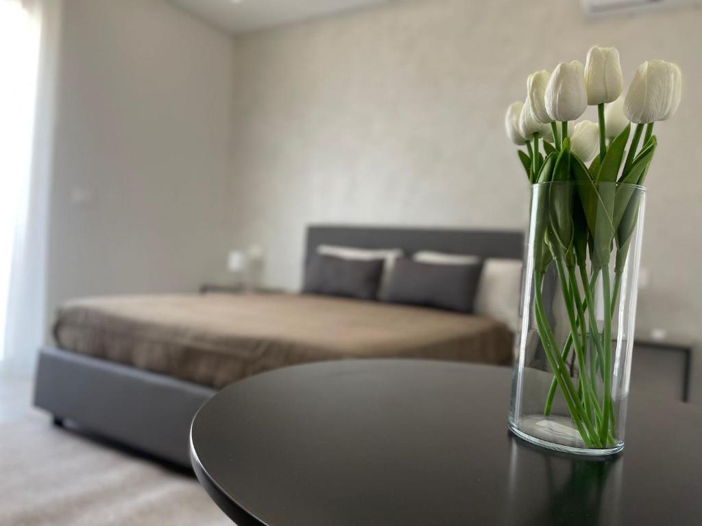 a vase of white tulips sitting on a table in a bedroom at B&B Campo Sportivo in Taurianova