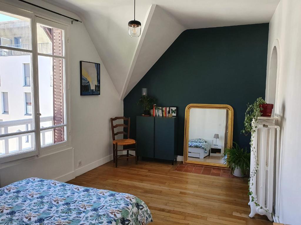 a bedroom with a green wall and a mirror at 2 chambres dans une maison proche de Paris et du Stade de France in Enghien-les-Bains