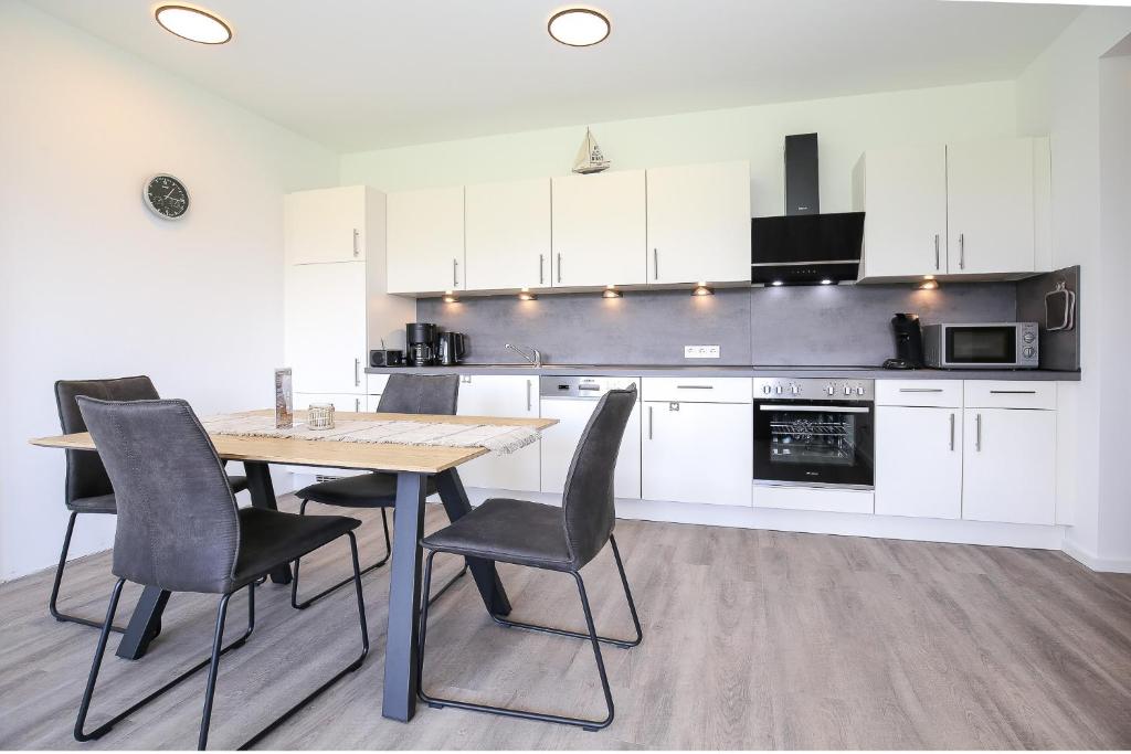 eine Küche mit weißen Schränken sowie einem Holztisch und Stühlen in der Unterkunft Weiße Villen Wohnung 19 in Boltenhagen