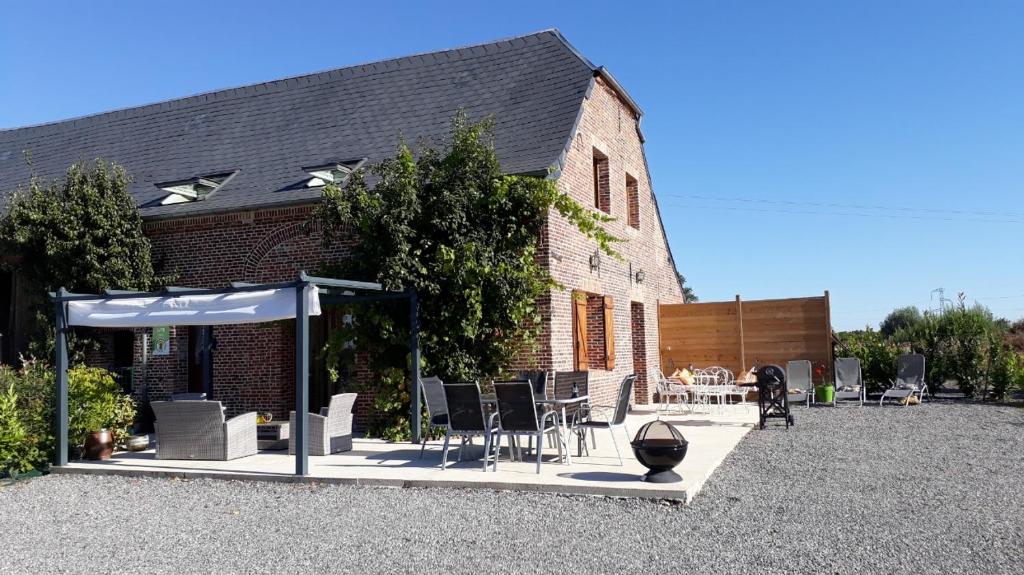 a building with a table and chairs in front of it at Gîte Version 70 in Mondrepuis