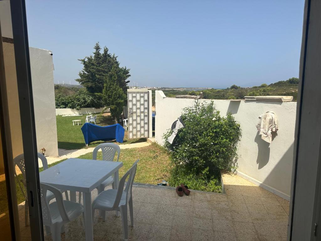 einen Tisch und Stühle auf einer Terrasse mit einem Tisch und Gartenblick in der Unterkunft DAR AROUA S3 avec jardin gazonné in El Haouaria