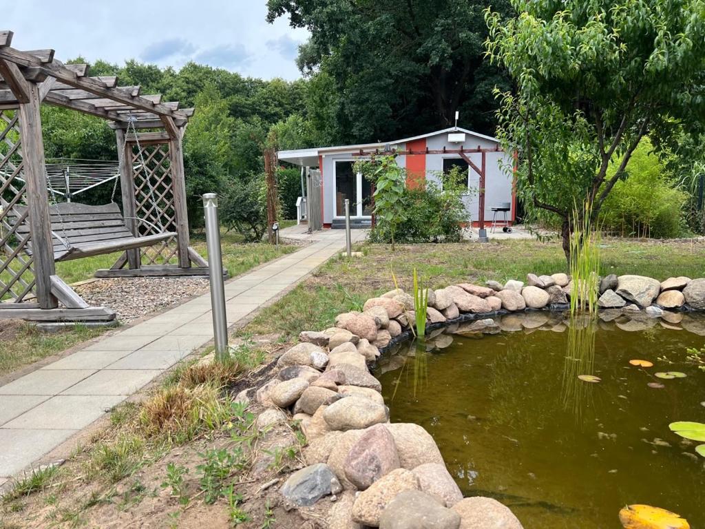 een vijver in een park met een bank en een gebouw bij Eichkobel in Rheinsberg