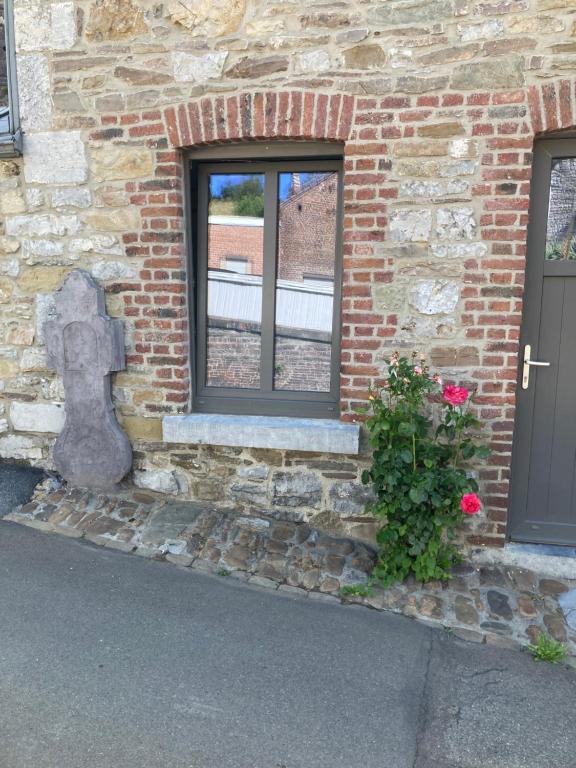 a brick building with a window and a bush at Charmante petite maison à Olne in Olne