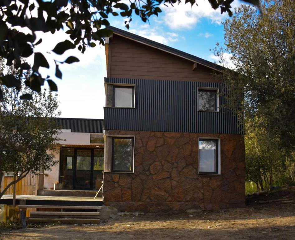 una casa construida en una pared de piedra con ventanas en Los soles de montaña, en Villa Pehuenia