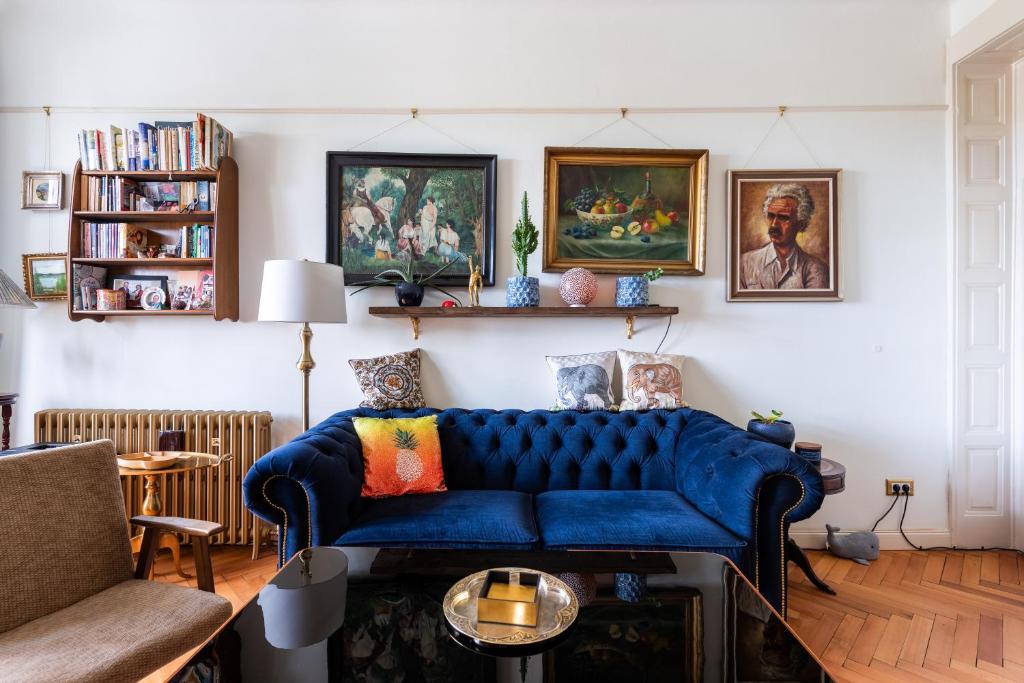 a living room with a blue couch and paintings at Victoria Design Stays - Premium Apartment Ohrada in Prague