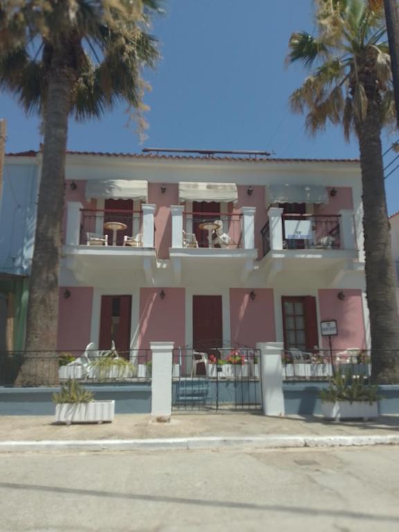 a pink building with palm trees in front of it at Maria's Studios in Skala Kallonis