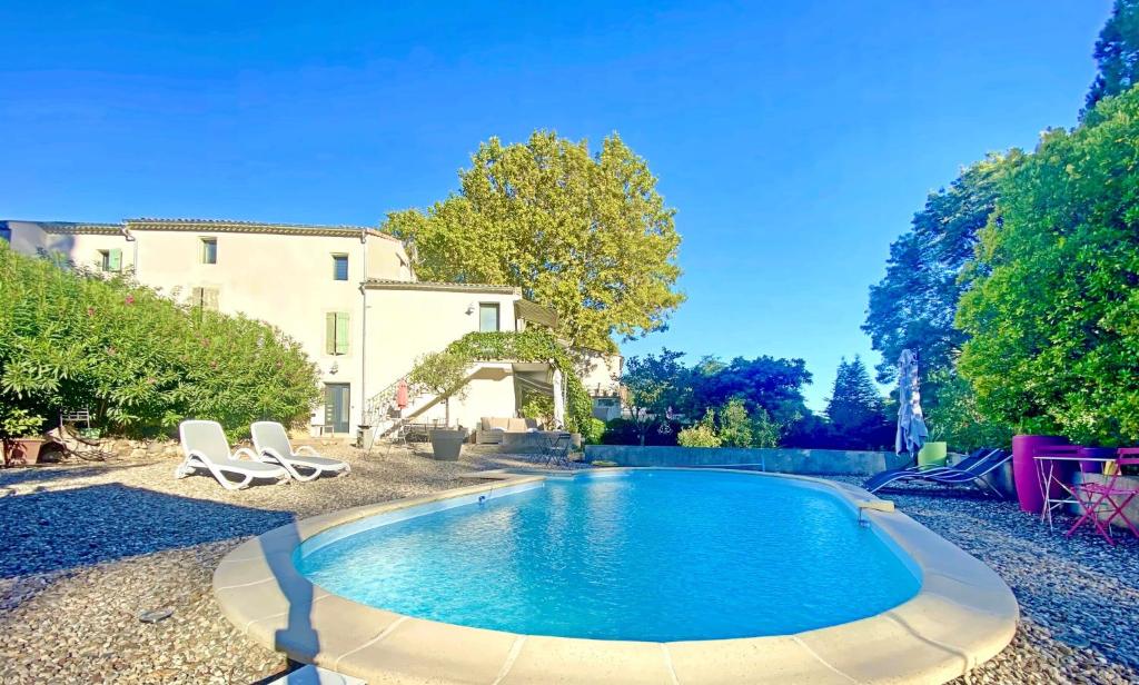 een zwembad met twee stoelen en een huis bij L'Escapade in Cazouls-d Herault