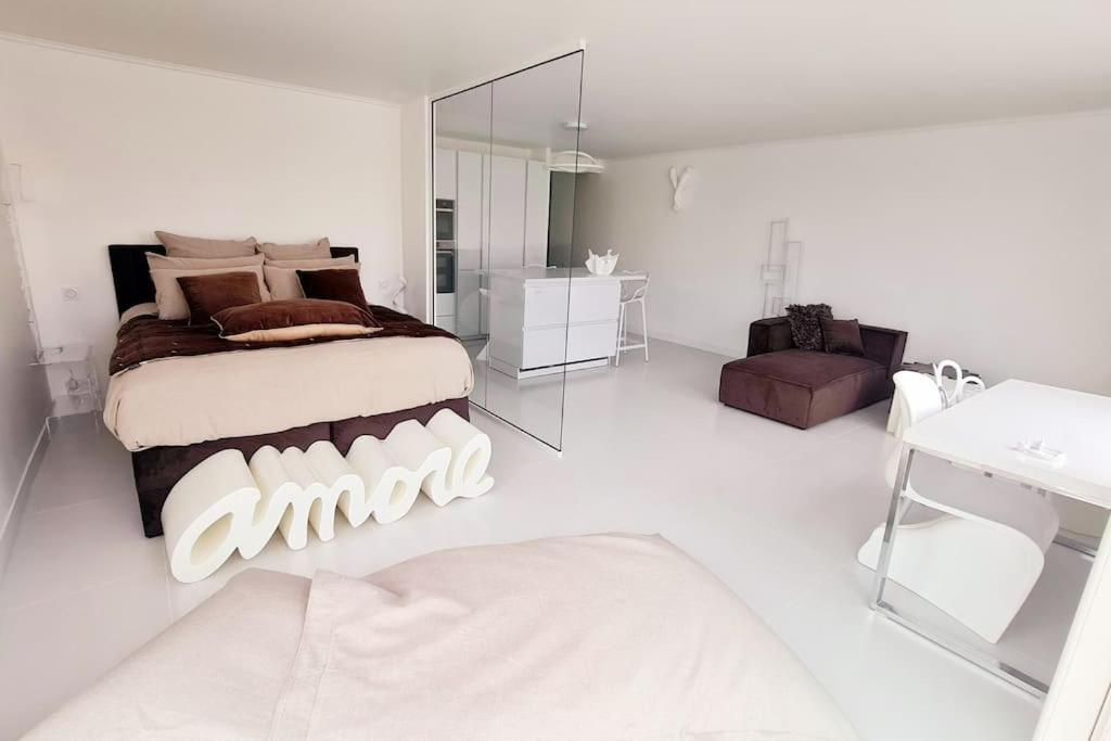 een witte slaapkamer met een bed en een spiegel bij Le rêve de Déborah in Cap d'Agde