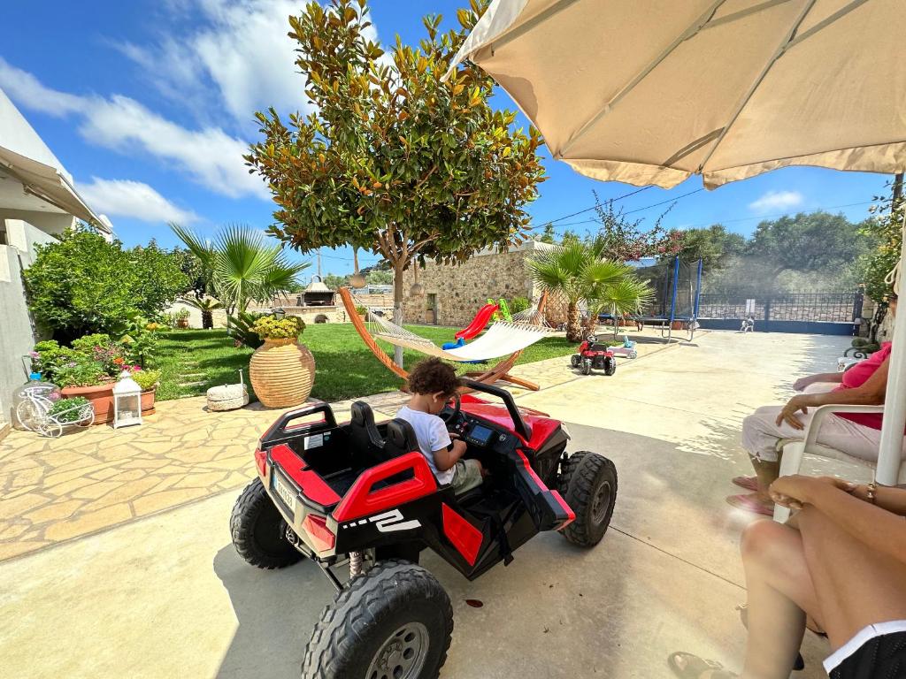 a child riding a toy atv in a backyard at BIO Garden New House in Gonia