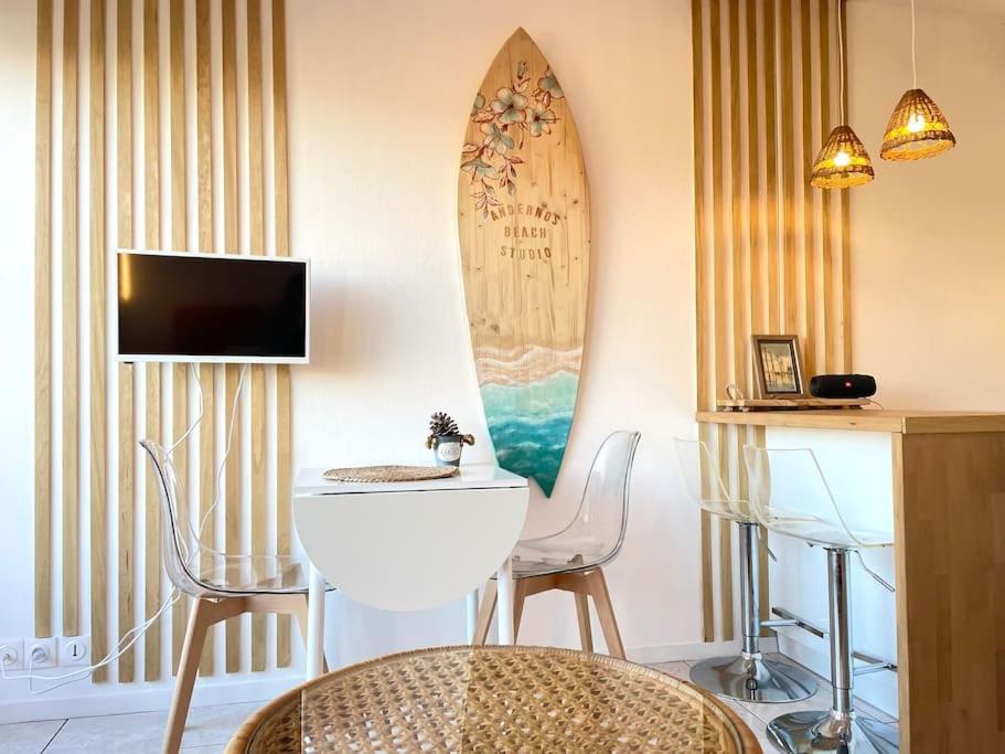 un salon avec une table et une planche de surf sur le mur dans l'établissement Andernos Beach Studio, à Andernos-les-Bains