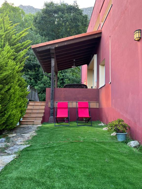 two pink chairs sitting on a lawn next to a building at Baigorri in El Llano