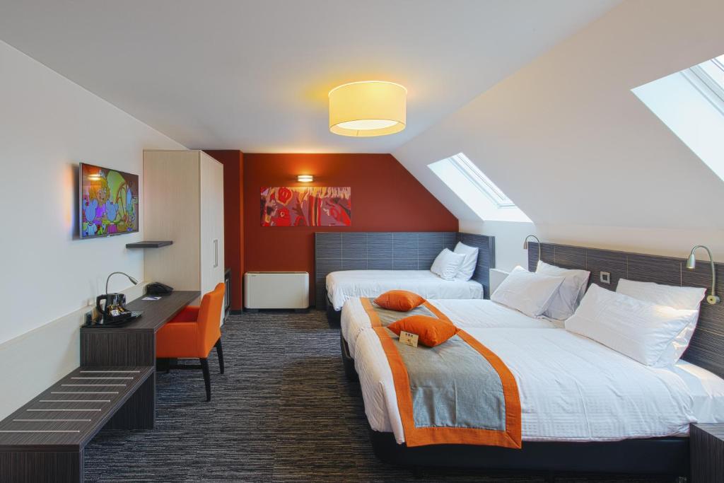 a hotel room with two beds and a desk at Orange Hotel La Louvière in La Louvière