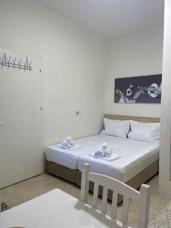 a white bedroom with a bed and a chair at Villa Apartments S&F City Centre in Tirana