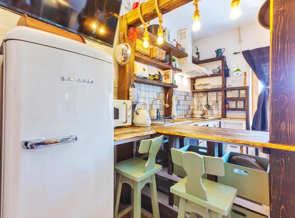 een keuken met een witte koelkast en groene krukken bij Lady Lavender House in Balatonfüred