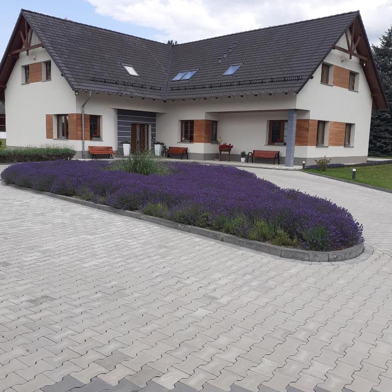 dom z fioletowymi kwiatami przed nim w obiekcie Agroturystyka Aura w mieście Kostrzyca