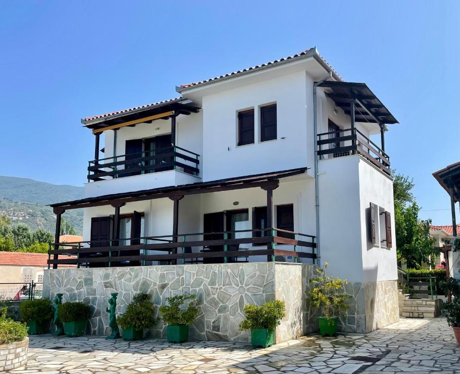 a white house with balconies and potted plants at Anemos Pelion Seaview in Kala Nera