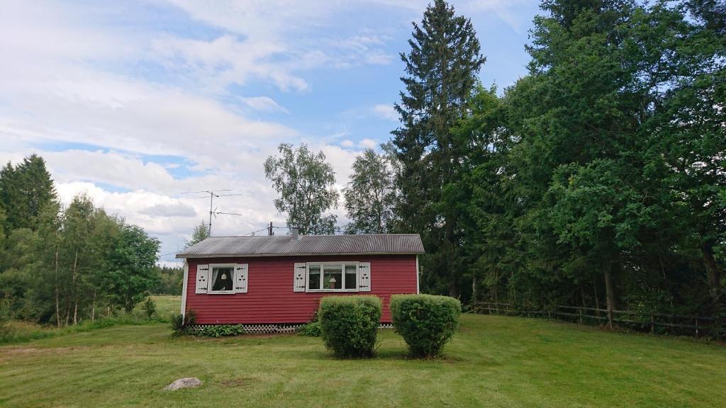 uma pequena casa vermelha no meio de um campo em Stuga vad vatten em Åsarp