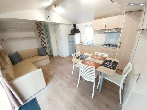 um quarto com uma mesa e cadeiras e uma cozinha em Mobil home climatisé 6pers. 3CH camping domaine de chaussy 5* Ardèche em Lagorce