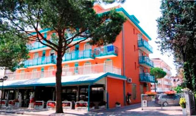 um grande edifício laranja com uma árvore em frente em Hotel Altinate em Lido di Jesolo