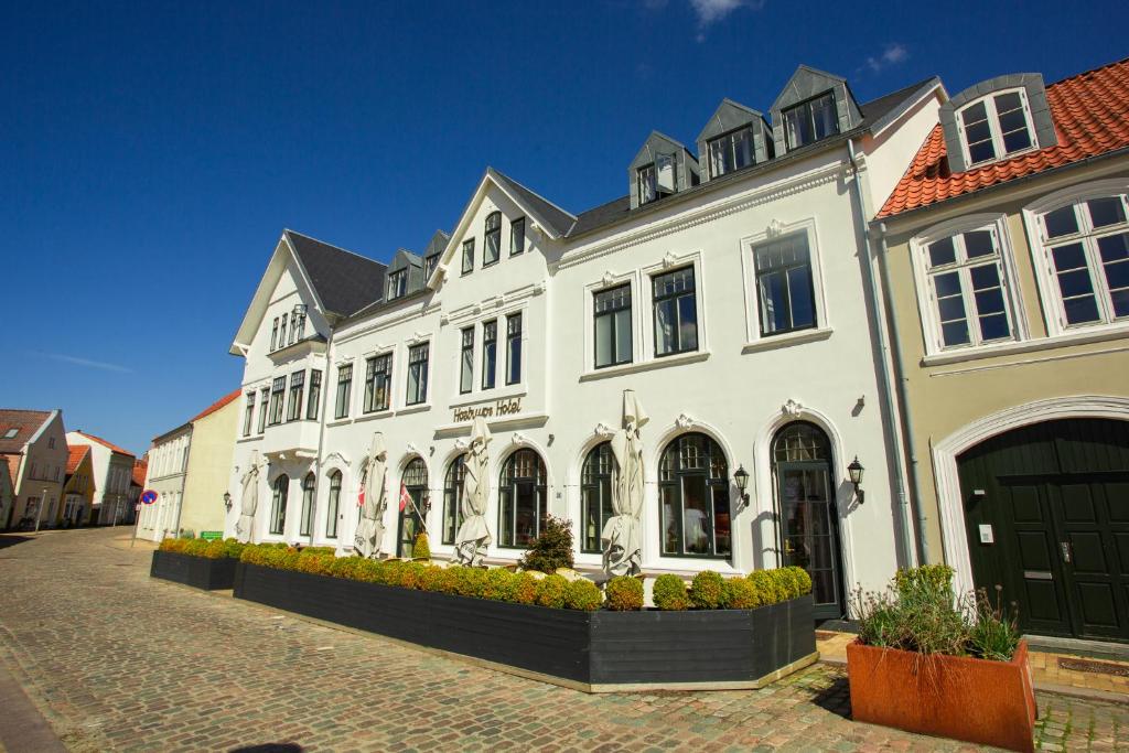 a large white building on a cobblestone street at Hostrups Hotel in Tønder