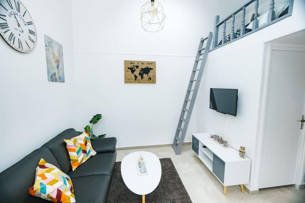 ein Wohnzimmer mit einem schwarzen Sofa und einem TV in der Unterkunft Le Coquet-T1 21m2-Proche Paris Metro 7 in Aubervilliers