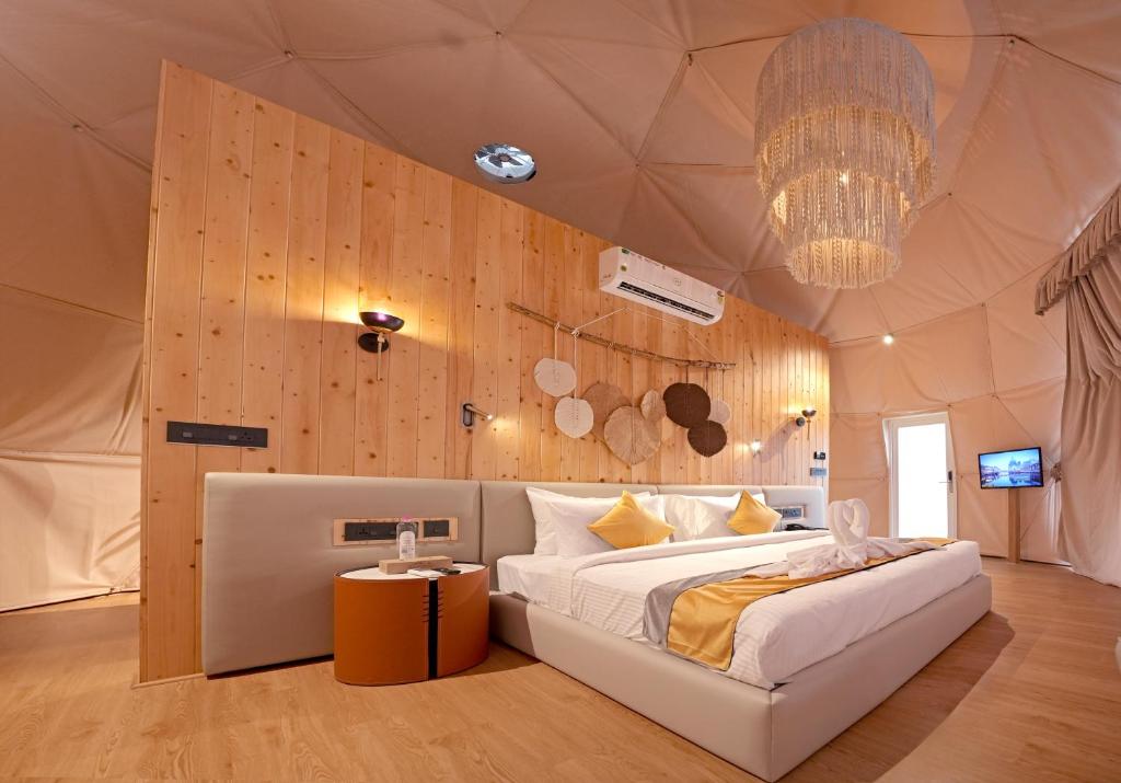 ein Schlafzimmer mit einem großen Bett und einem Kronleuchter in der Unterkunft Le Villagio Resort & Domes in Sultan Bathery