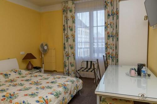 a bedroom with a bed and a table and a window at Hôtel de la cloche in Vitry-le-François