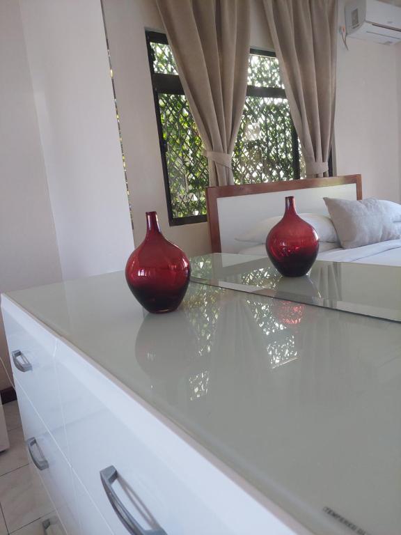 Reef Hills Residence FAMILY HOME في أو كاب: وجود مزهريتين حمرا على منضدة زجاجية في غرفة النوم