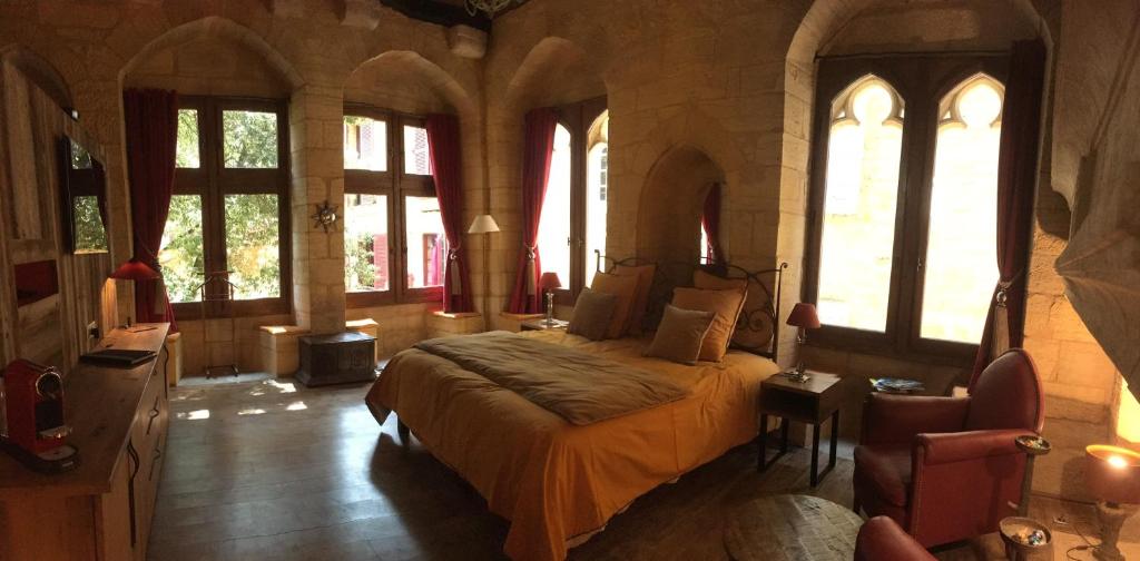um quarto com uma cama num quarto com janelas em Hôtel particulier Fénelon (XIIIe) em Sarlat-la-Canéda