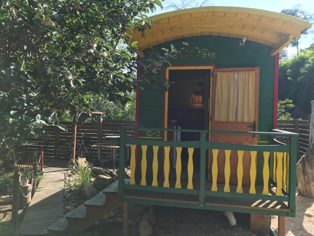 ein kleines grünes Haus mit einer Veranda und einer Tür in der Unterkunft La roulotte de moulin rouge in Audelange