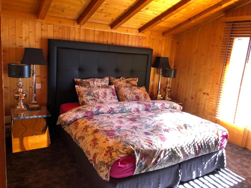 Chalet Bellevue, Villars-sur-Ollon في Ollon: غرفة نوم بسرير كبير في غرفة خشبية