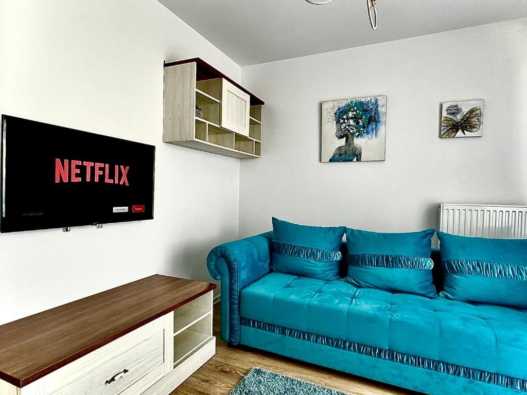 een woonkamer met een blauwe bank en een tv bij 4FriendsCoresiBrasov Blue in Braşov