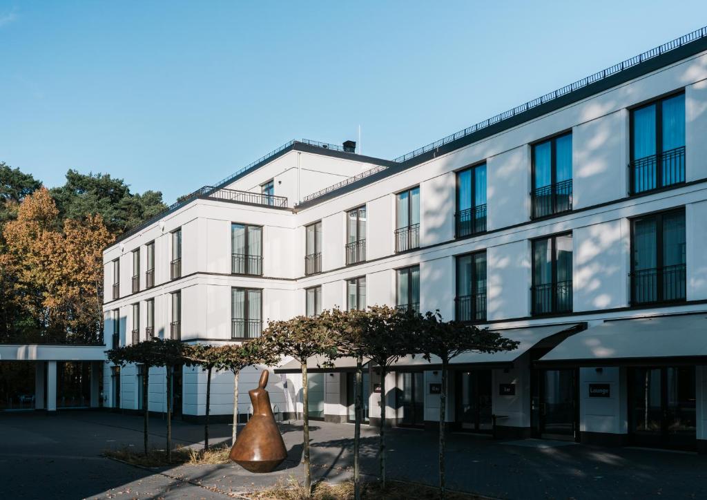 un gran edificio blanco con una estatua delante de él en Velotel Bad Saarow, en Bad Saarow