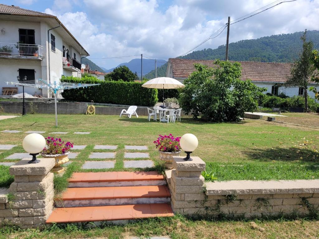 un jardín con mesa y sombrilla en Appartamento in villa a 20 min da Levanto e dalle 5 Terre-Sesta Godano en Sesta Godano