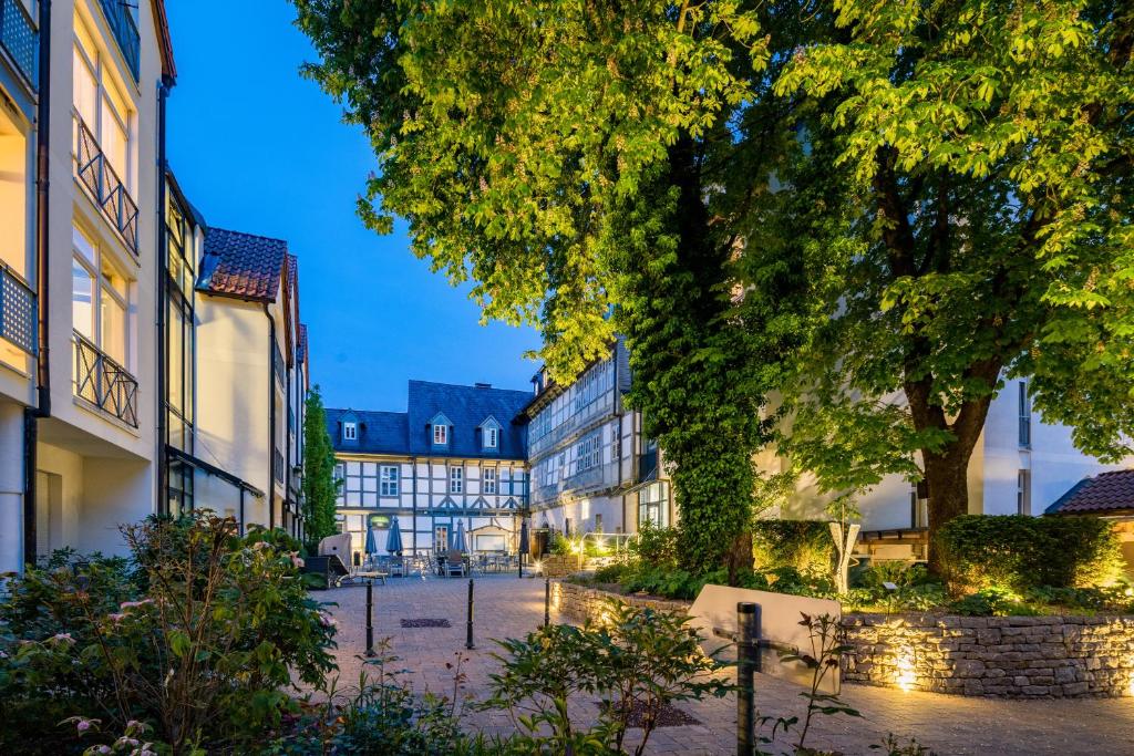 uma rua da cidade com edifícios e árvores à noite em GDA Hotel Schwiecheldthaus em Goslar