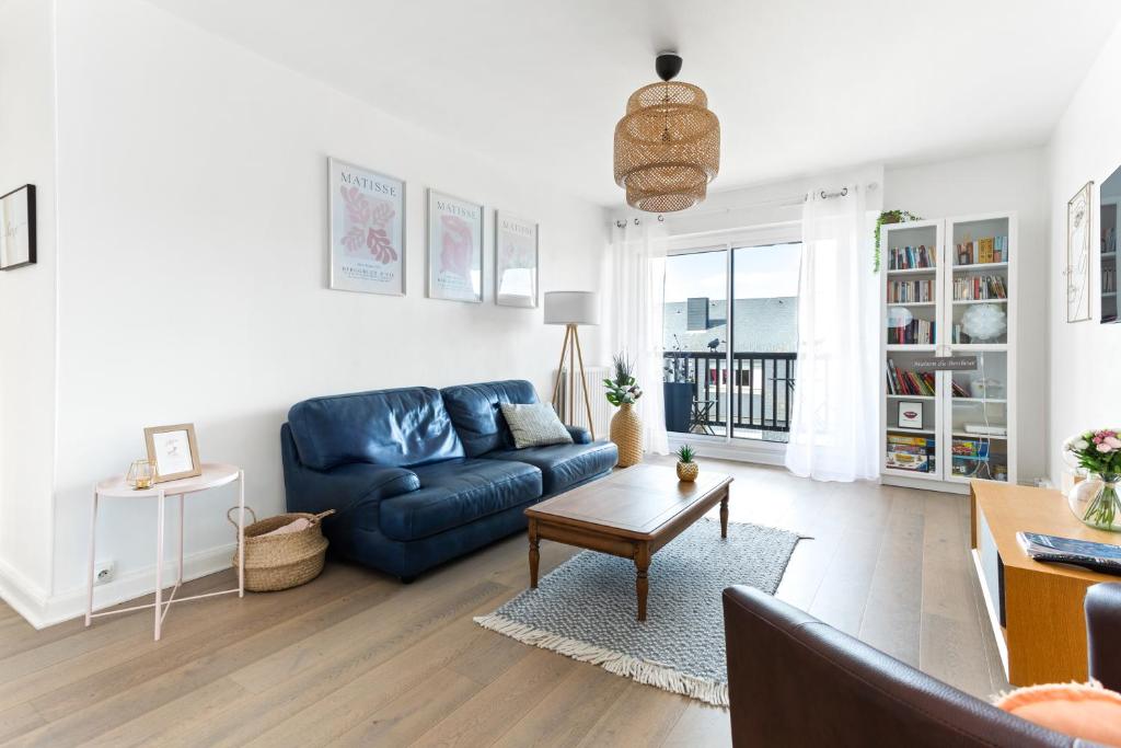 a living room with a blue couch and a table at LE COSY avec piscine, balcon et parking in Trouville-sur-Mer