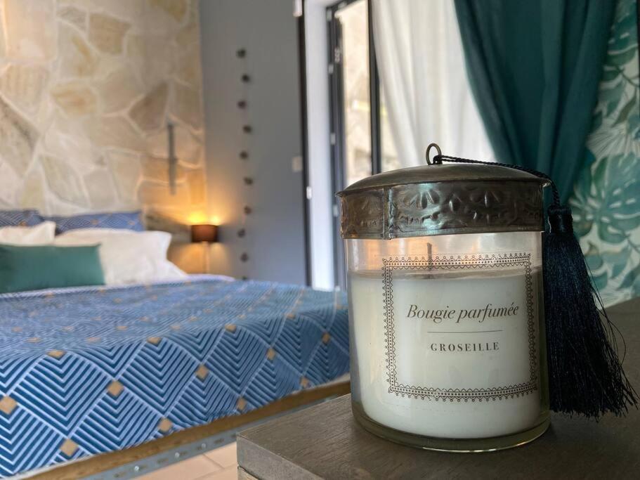 a candle sitting on a table next to a bed at Cocooning Tropic Studio avec Jacuzzi privatif in Saint-Louis