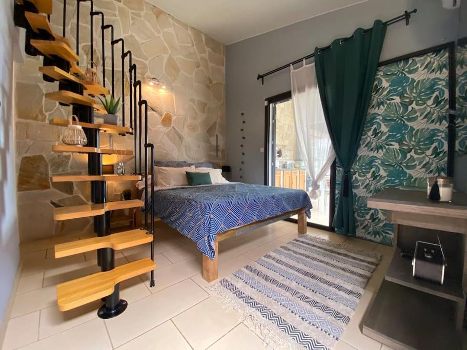 a bedroom with a bed and a staircase in a room at Cocooning Tropic Studio avec Jacuzzi privatif in Saint-Louis