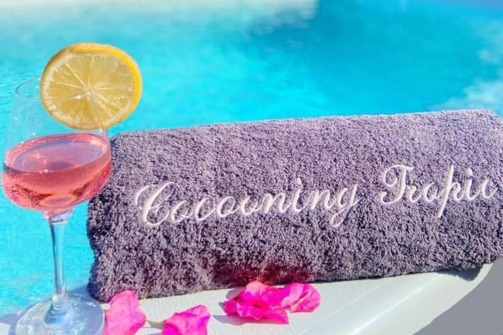 a purple towel with a glass of wine next to a pool at Cocooning Tropic Studio avec Jacuzzi privatif in Saint-Louis