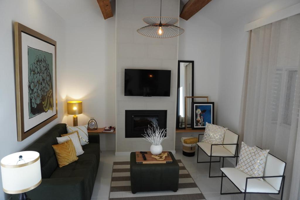 a living room with a couch and chairs and a tv at Casa Amélia in Feteira Grande