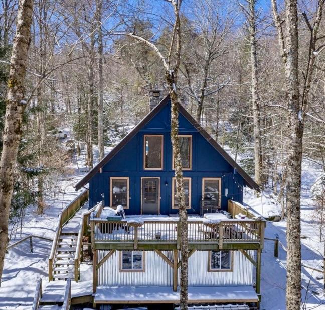 a blue house with a deck in the snow at Abundant Acres Retreat in Beech Mountain