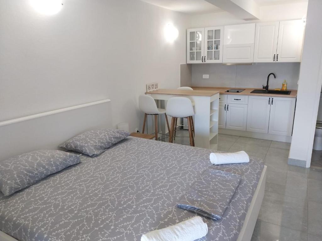 a bedroom with a bed and a kitchen with white cabinets at Apartments Lumbarda in Lumbarda